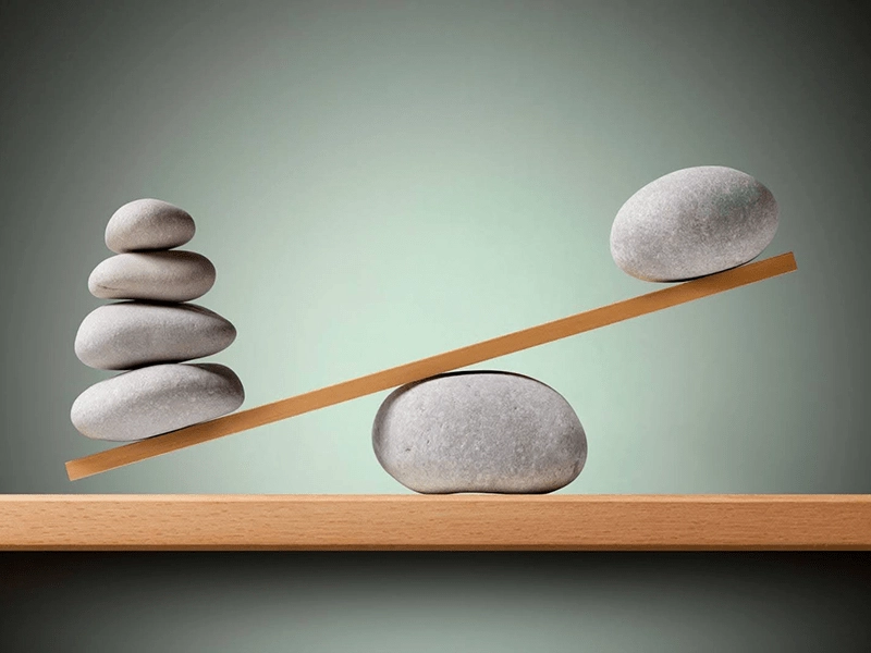 smooth stones balancing on a plank of wood on a stone